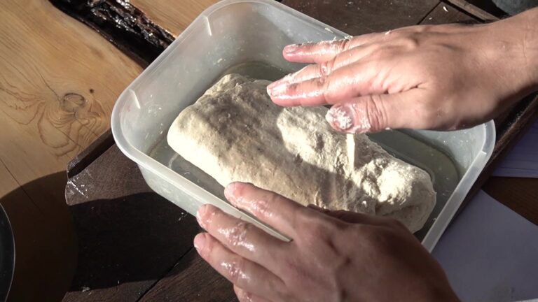 Haciendo los pliegues a la masa de ciabatta sin gluten en un táper aceitado