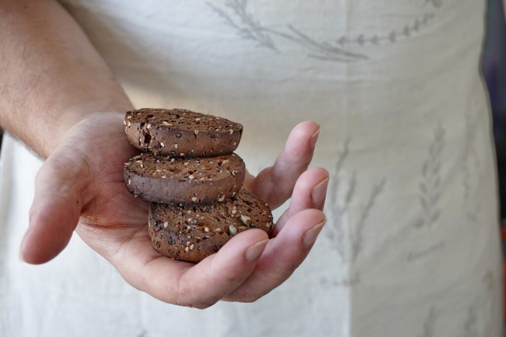 Tres cookies de algarroba sin gluten apiladas en la mano