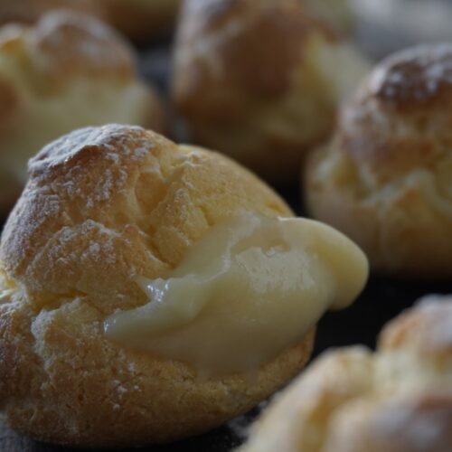 Bombas sin gluten rellenas de crema pastelera sobre una tabla de madera