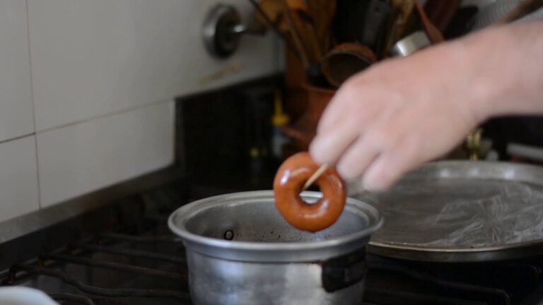 Dona sin gluten recién frita, dorada, saliendo de la olla con aceite