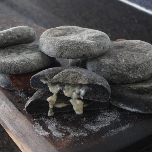 Pancitos sin gluten hechos en sartén, uno relleno de queso, sobre una tabla